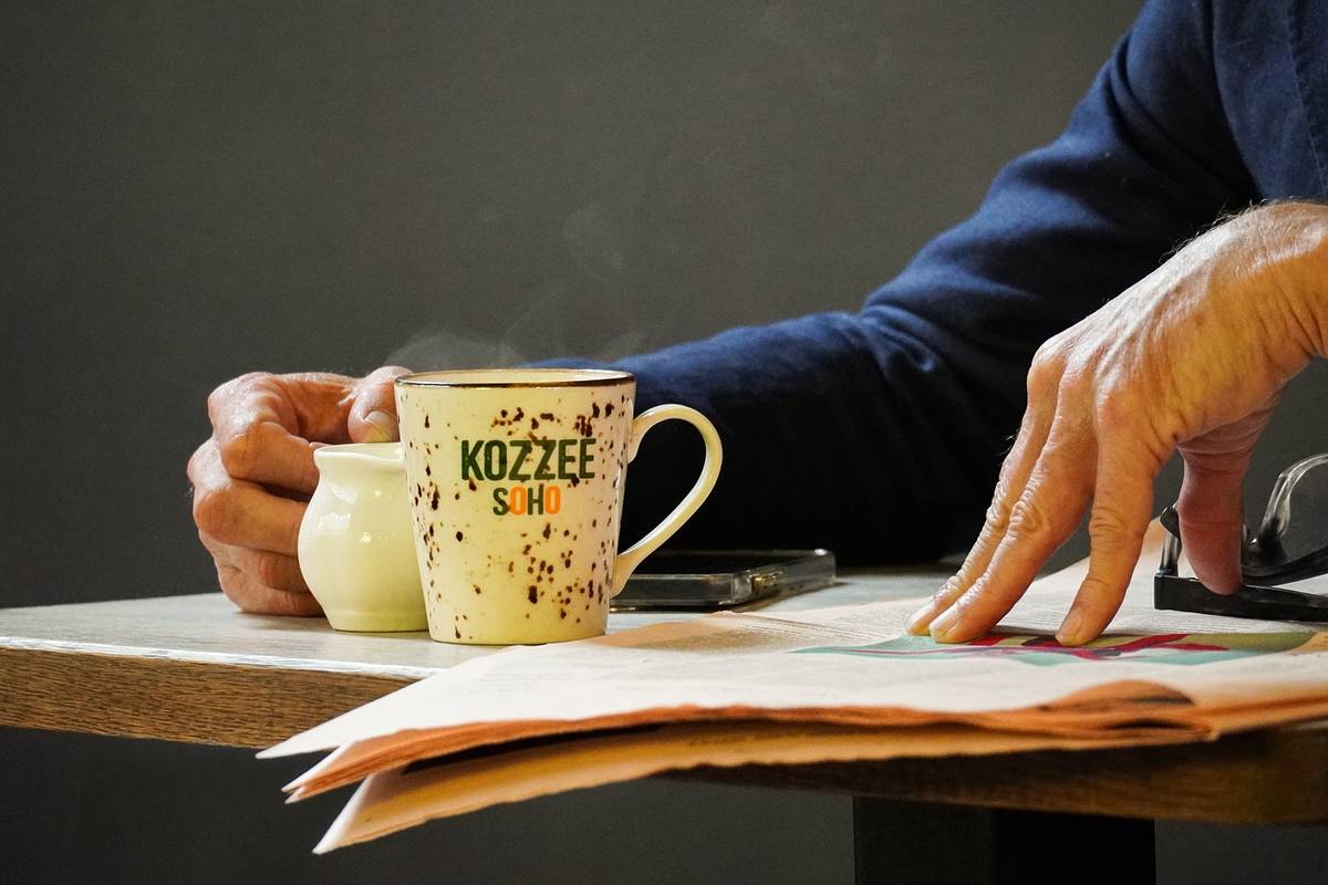 Customer enjoying a cup of coffee and reading the paper at Kozzee café in Soho, London.