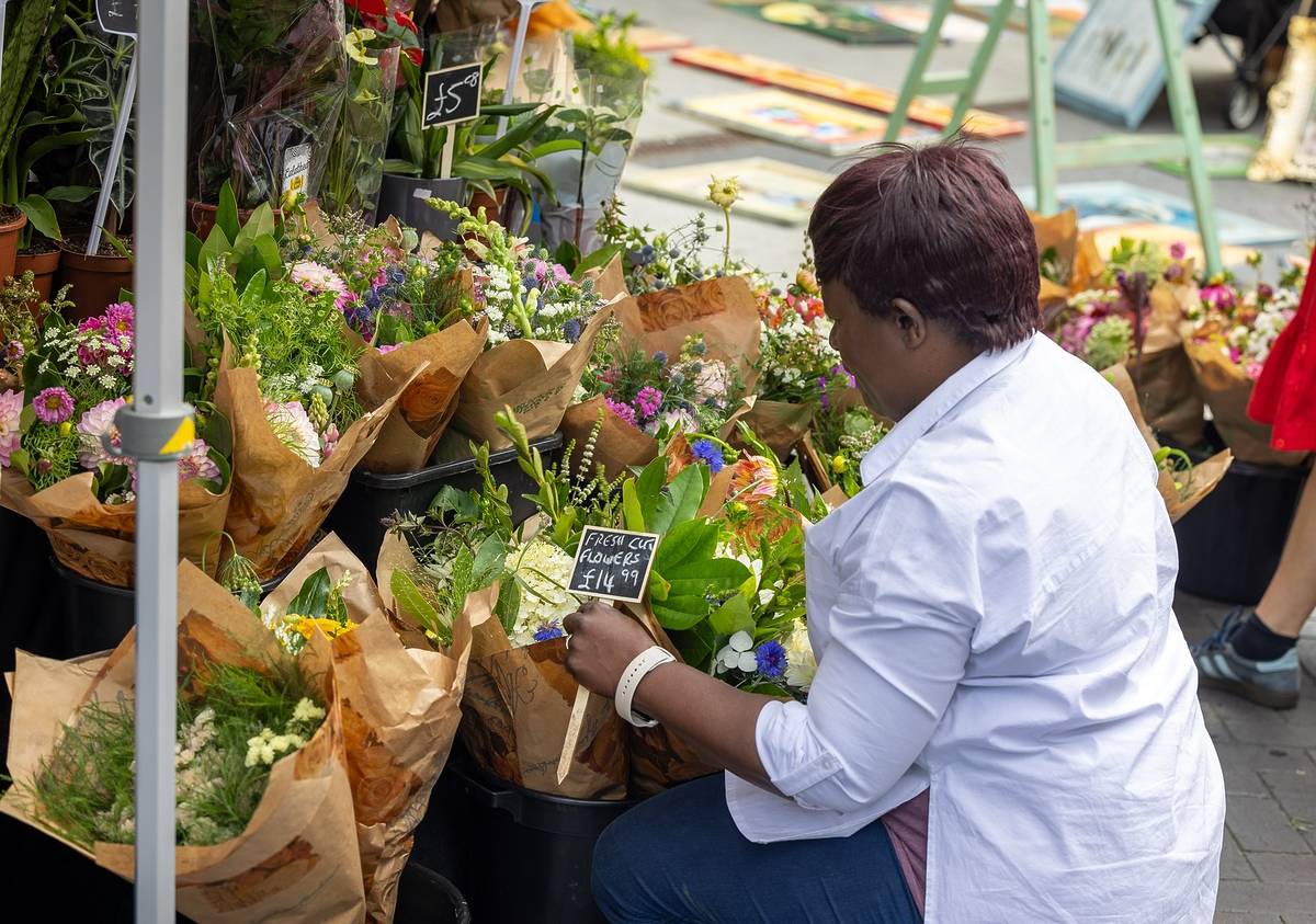 Person browsing flower stall at Wembley Park Market, London.