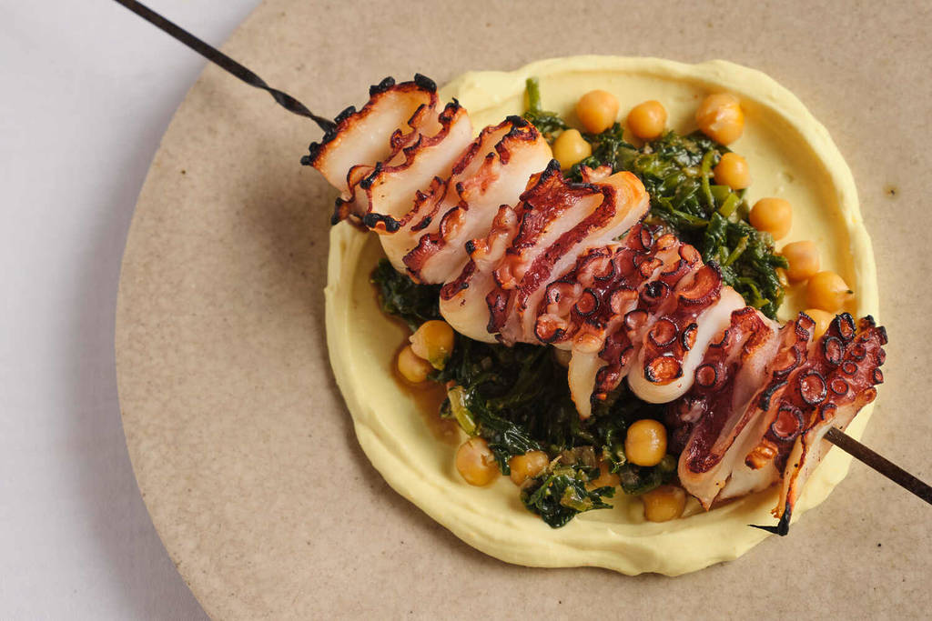 een octopusspies met chiclpeas, groenten en een soort puree