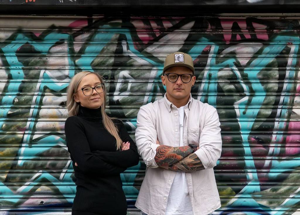 restauranteurs Lidia and Simone Crepaldi stand with their arms crossed looking at the camera in front of a graffitied shutter