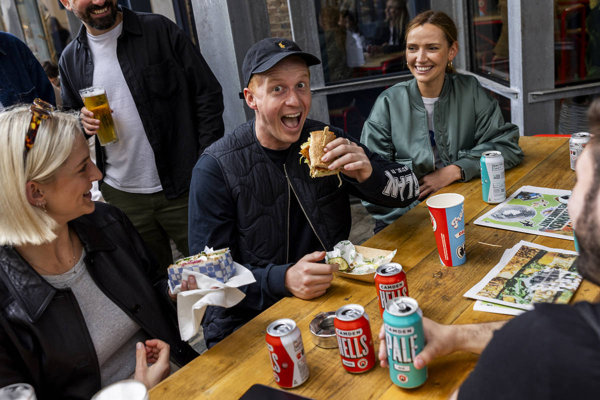 a man grins as he tucks into a big sandwich at the Sarnie Party festival