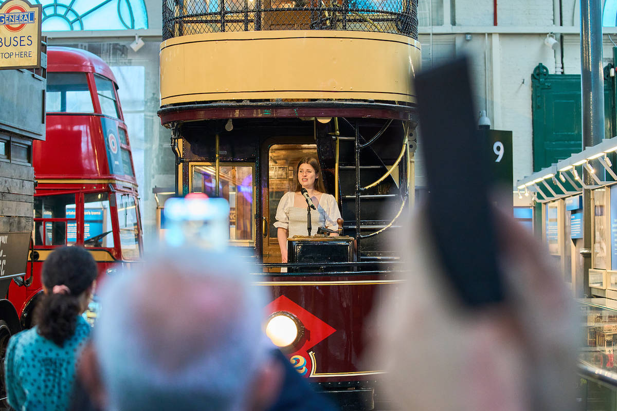 a woman singing on the back of a former London bus at the London Transport Museum