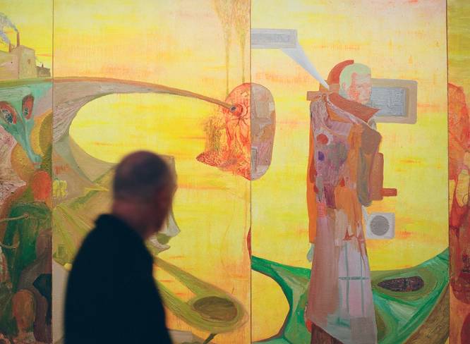 A visitor at Art Basel Paris observing a large yellow and orange art piece