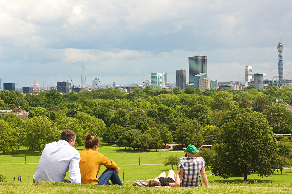 People relaxing on Primrose Hillm with views of London.