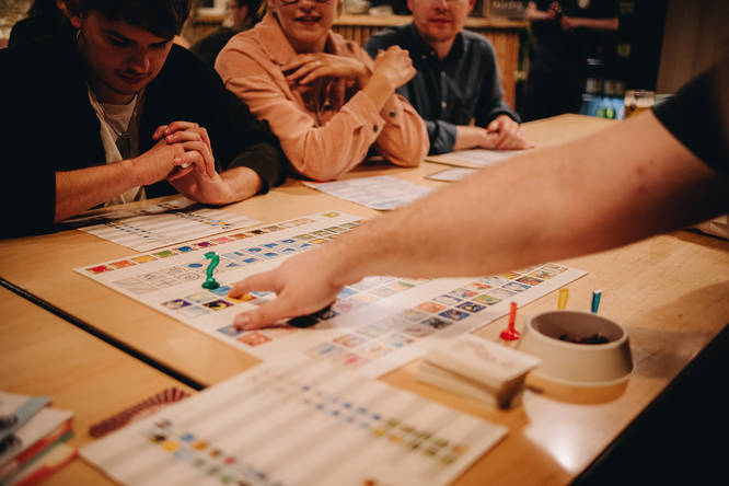 players sat around a table while playing a board game at draughts