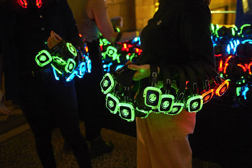 Un'immagine di due persone che tengono in mano delle cuffie luminose da silent disco