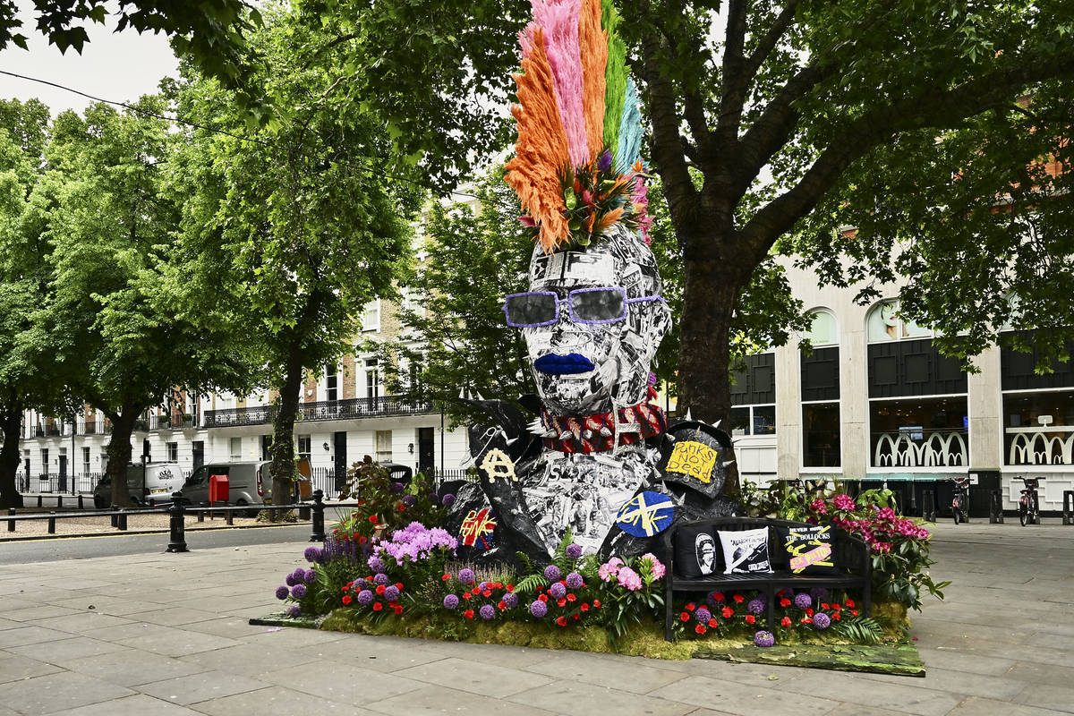 an enormous tree-sized bust of a punk, with a colourful floral mohwak, with a steel visage