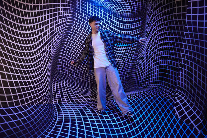 a young man stands in a warp-like room at the Twist Museum