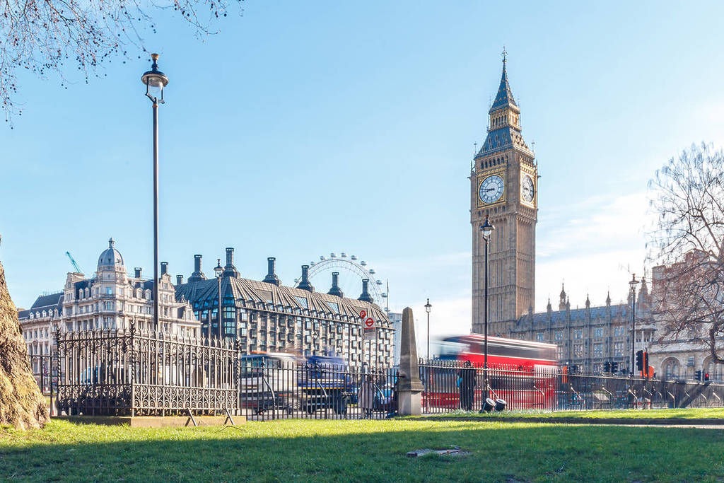 Foto de uma manhã ensolarada de primavera com o Big Ben e um autocarro vermelho passando em Londres