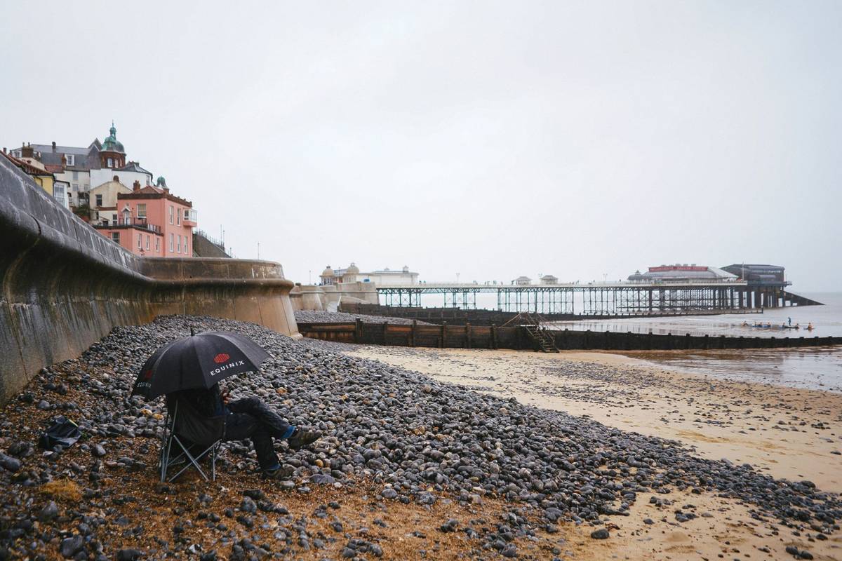 A man with a n umbrella on the beach in grey UK weather