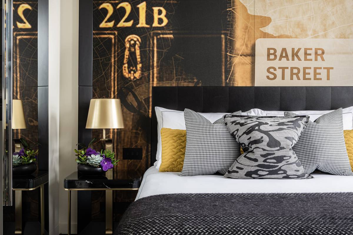 A bed at the Holmes Hotel with a wall dedicated to Sherlock Holmes behind it