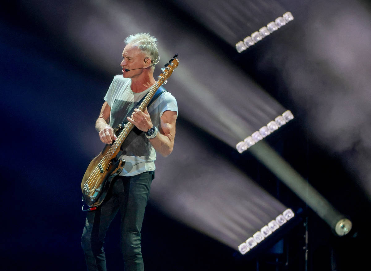 Sting playing a guitar on stage