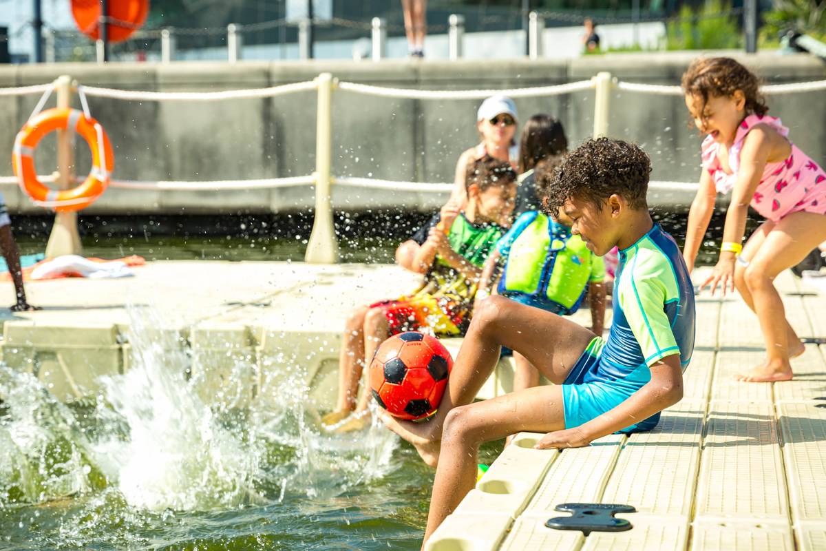 Some children sat on the side of a lido in London