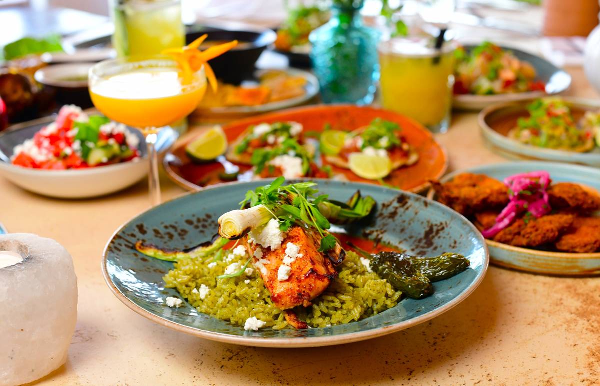 a platter of mexican food on a table in front of other plates and glasses