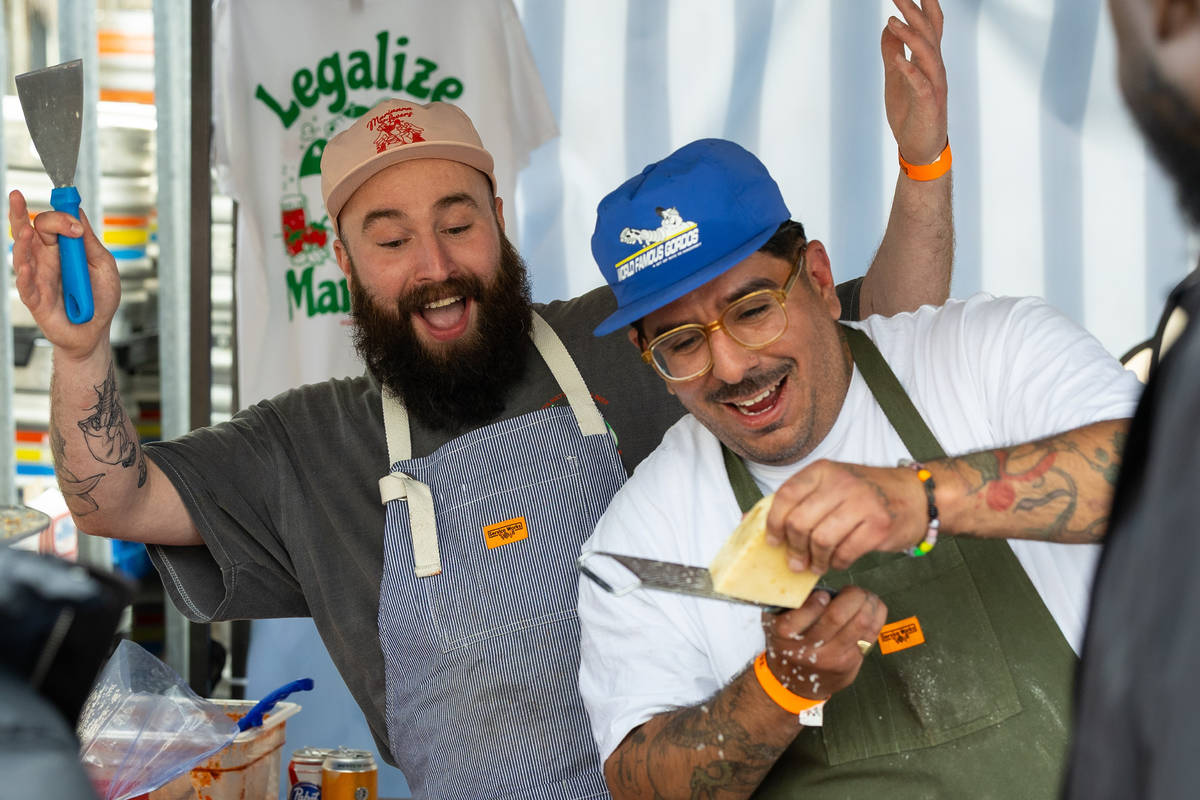 two pizza vendors goofing around at a slice-o-mania stall while grating parmesan