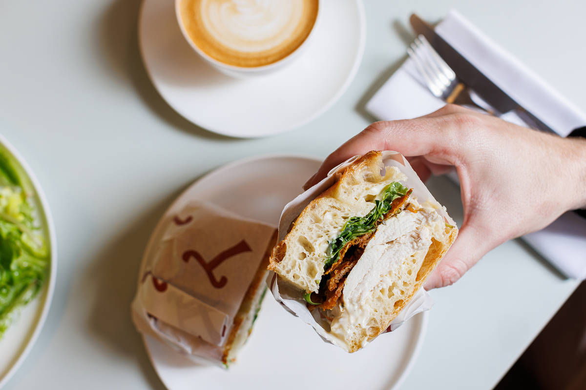 half a sandwich in greaseproof paper being held in a hand to reveal the fillings