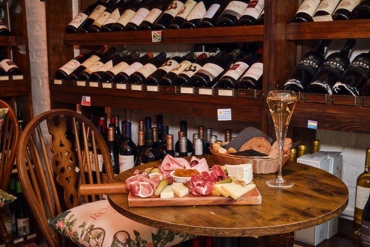 A charcuterie board and a glass of wine on a table inside a wine bar