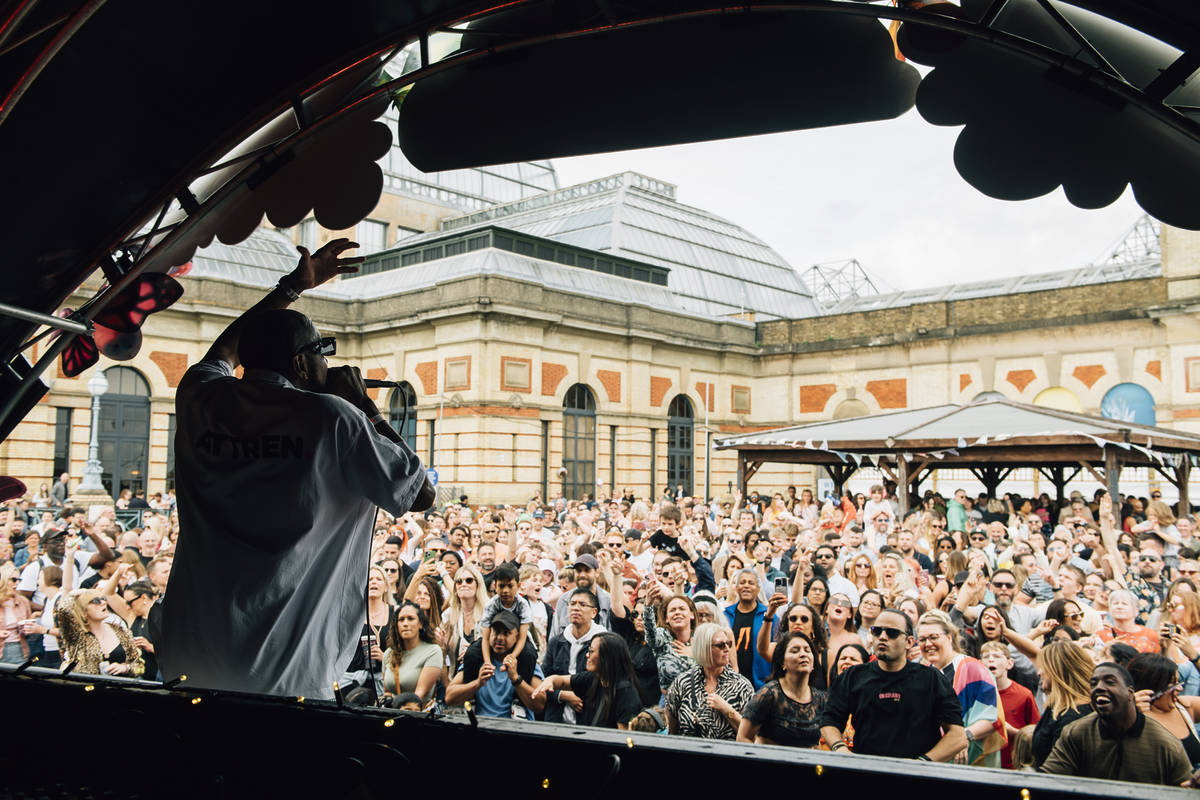 people gathered in front of a stage at ally pally kaleidoscope festival while someone performs