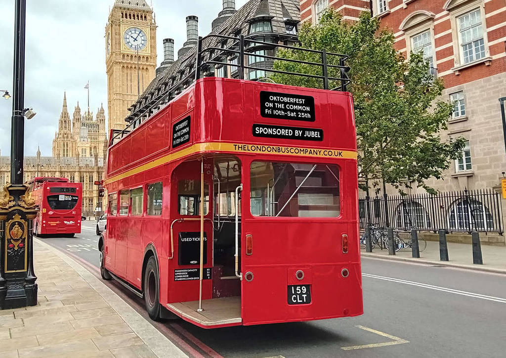 ein roter Doppeldeckerbus, der vor dem Big Ben vorbeifährt