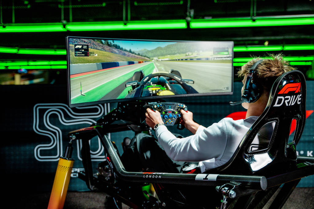 a young man in a gaming chair playing a racing VR game on a screen