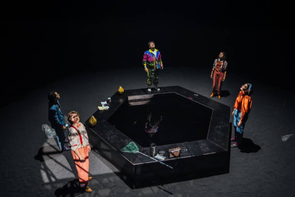 actors on stage around a mysterious angular black object