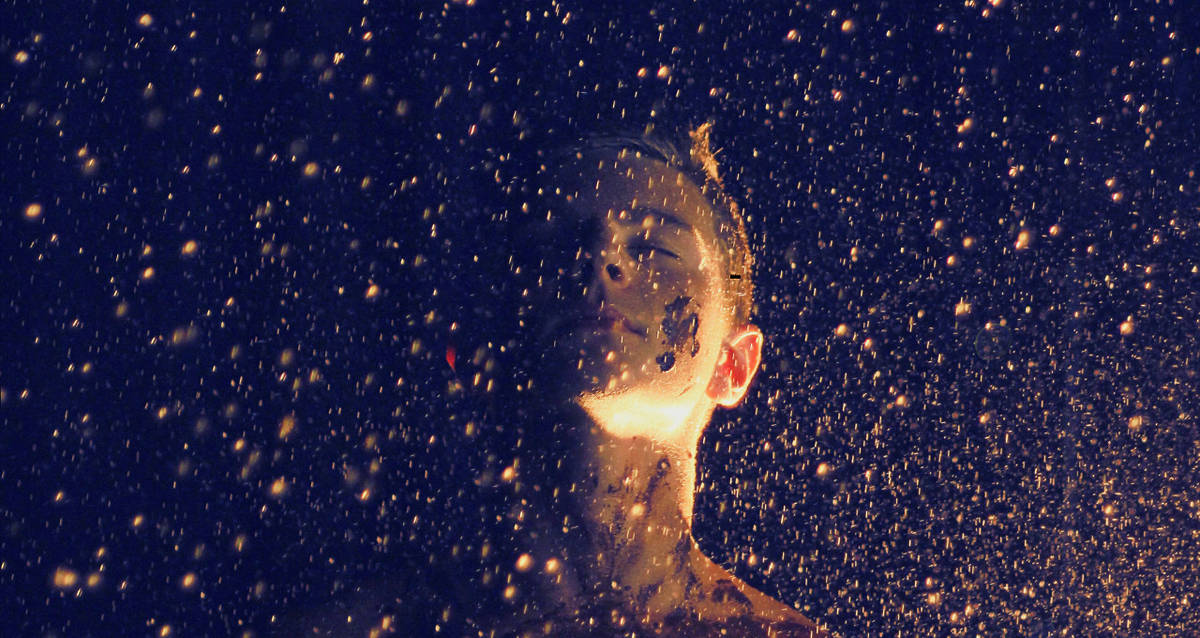 a close up shot of an actor's face as glitter falls onto and around them in a performance