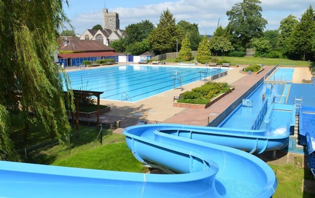 Un tobogán acuático y una piscina rodeada de árboles en Guildford Lido