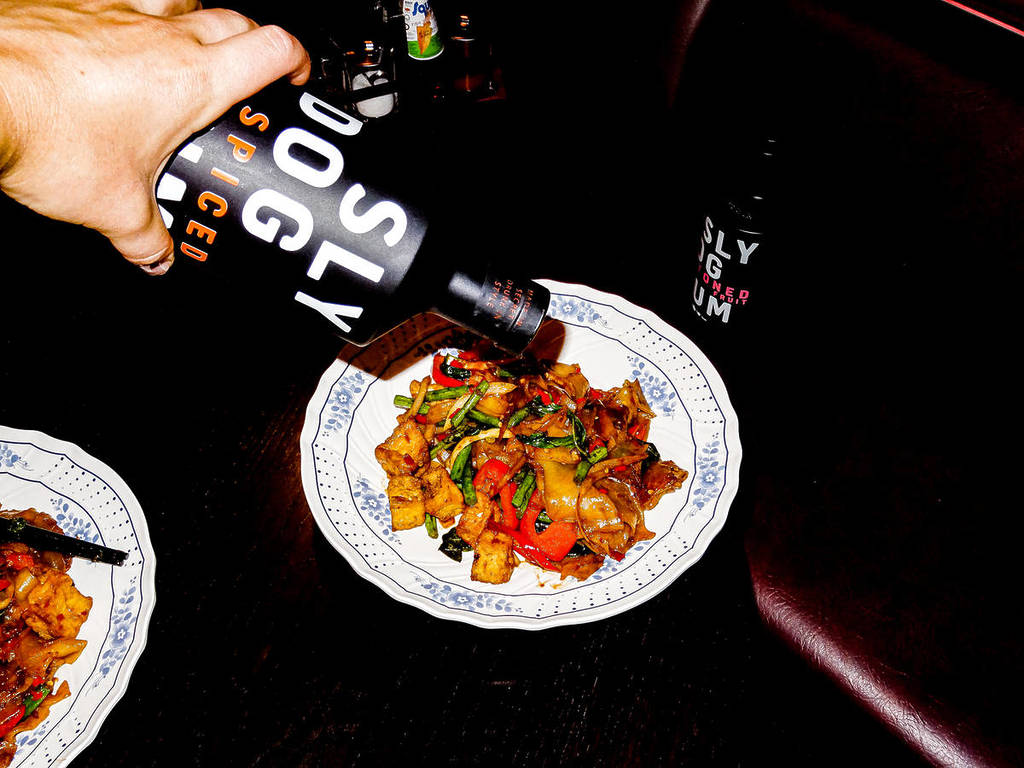alguien vierte una botella de ron sobre un plato de fideos