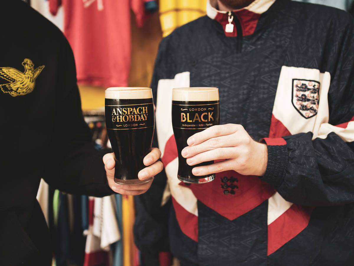 two people cheersing together pints of a dark porter