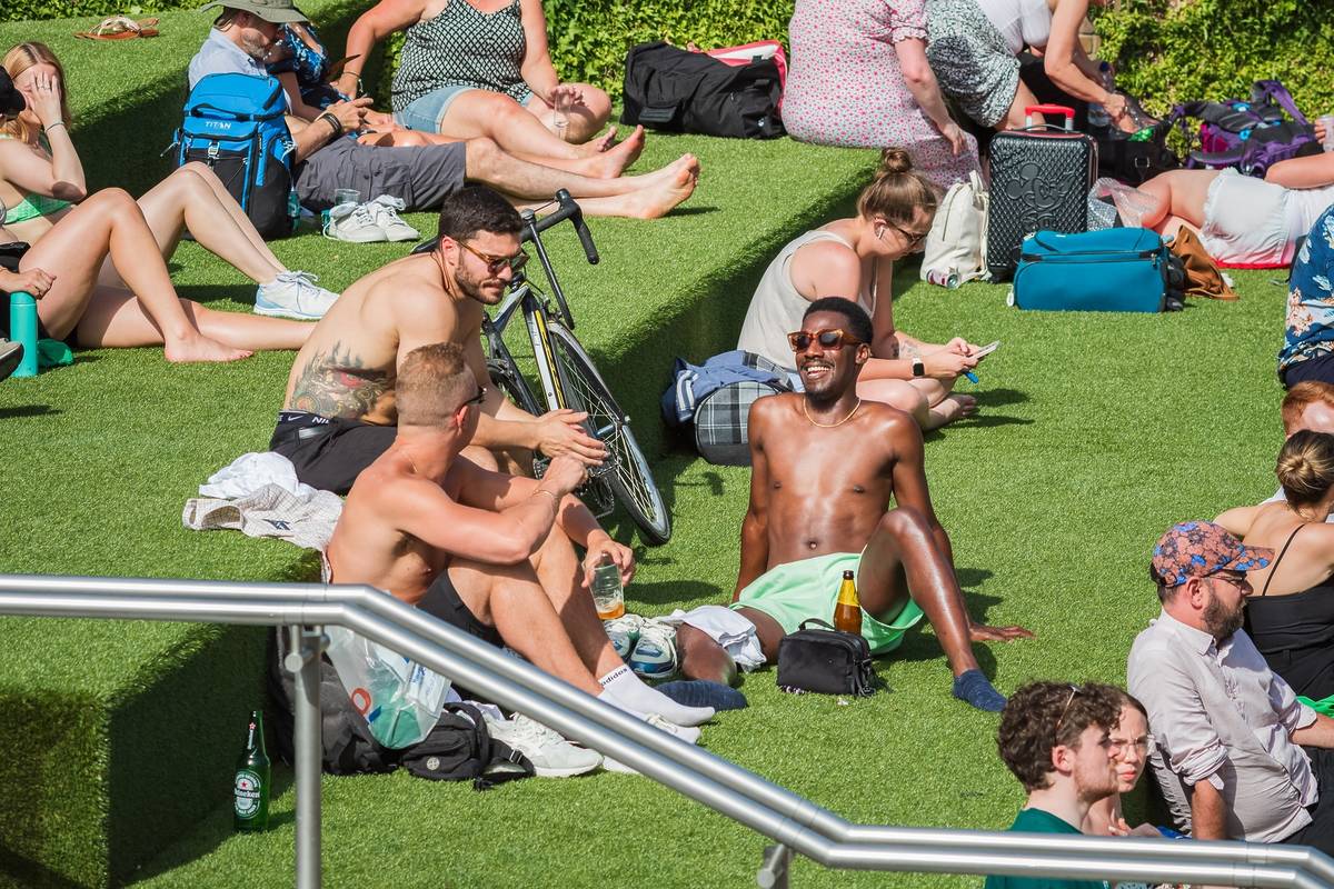 people sat topless on the Canalside Steps of Granary Square in Kings Cross during a london heatwave