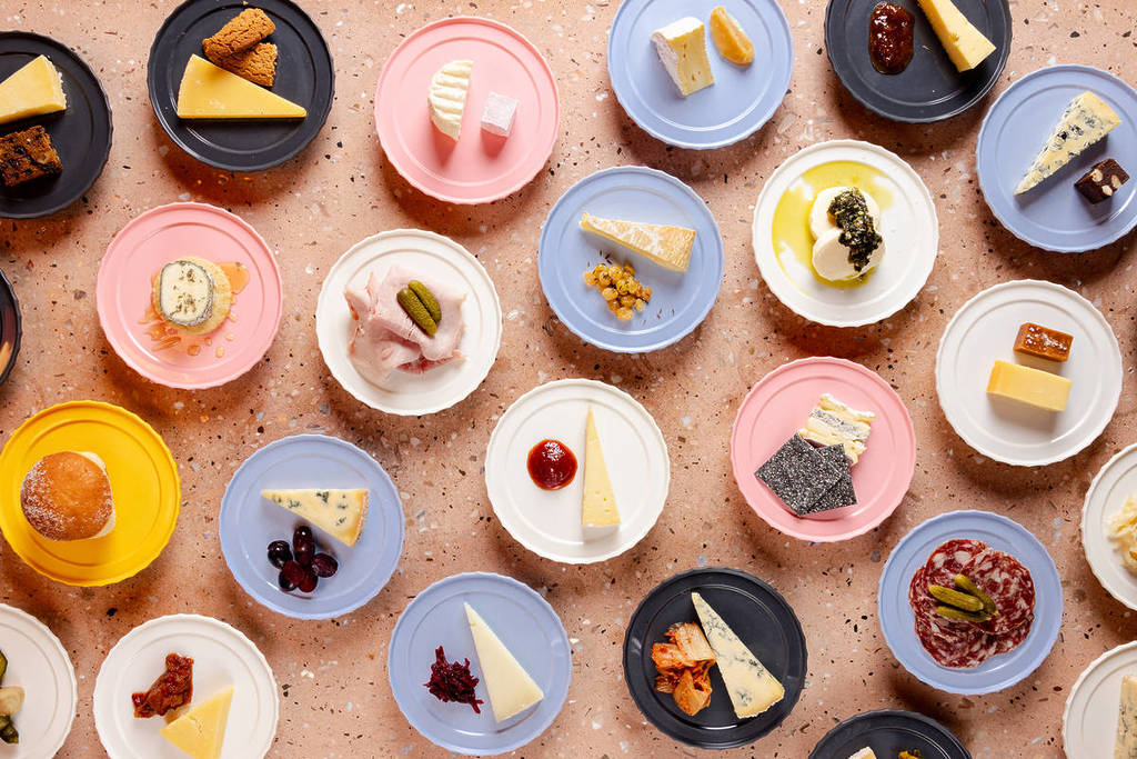 una variedad de platos rosas, azules y blancos con queso