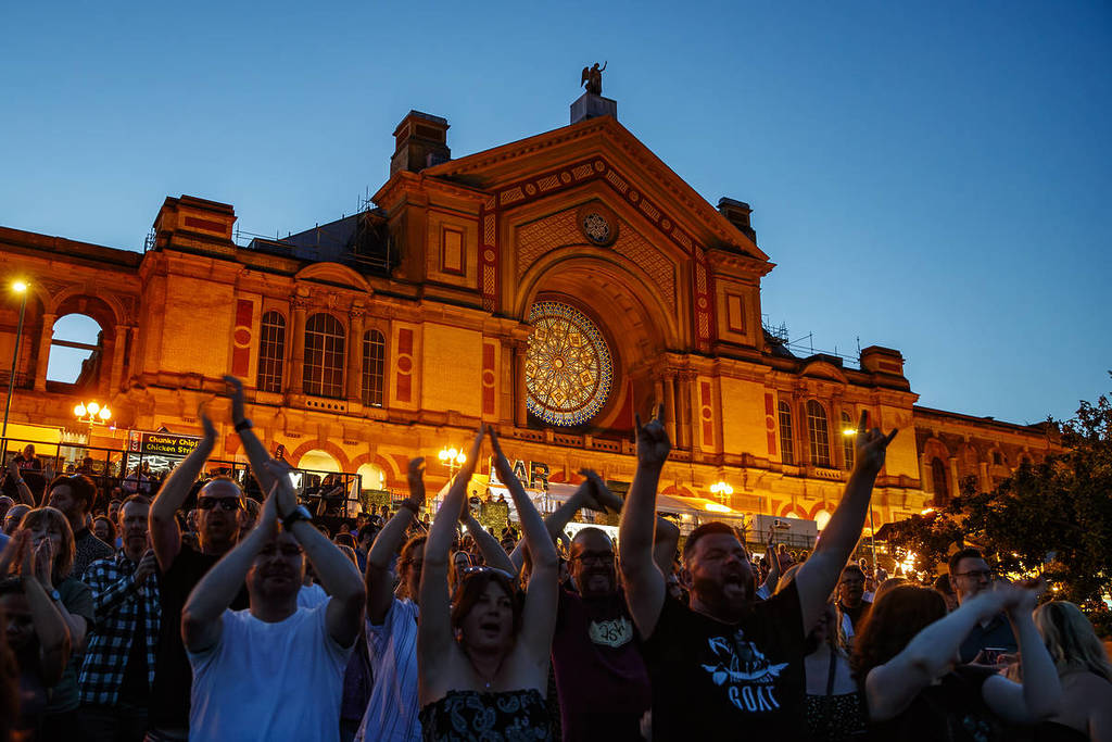 A crowd of people after dusk with Alexandra Palace in the background