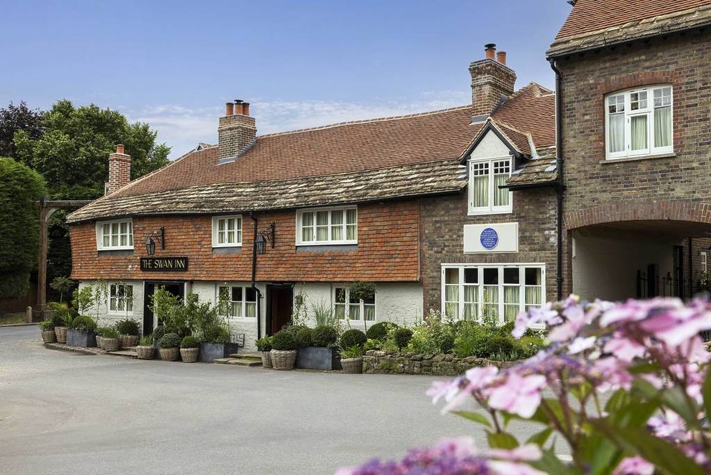 De buitenkant van de Swan Inn pub met paarse bloemen op de voorgrond