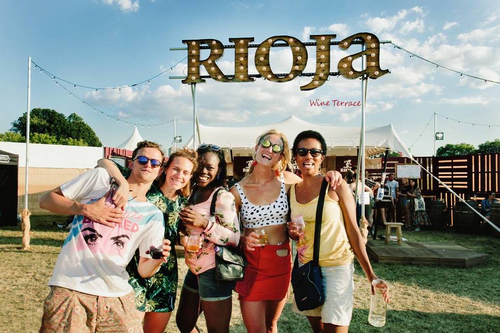 A group of friends standing beneath a big sign that reads 'Rioja Wine Terrace'