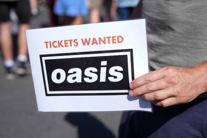 Oasis fan looking for tickets in Manchester with a sign saying 'Tickets Wanted'