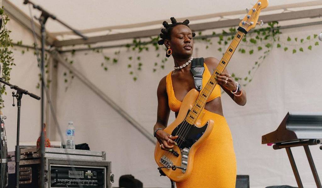 a lady in a yellow dress playing a yellow bass guitar