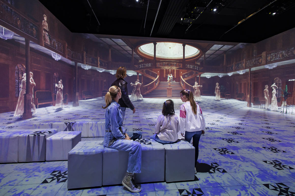 a group of people look at a projection of the grand staircase at the Legend of the Titanic Exhibition