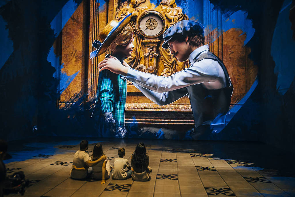 quatro pessoas sentadas no chão a olhar para uma projeção de um pai e uma filha na exposição Legend of the Titanic