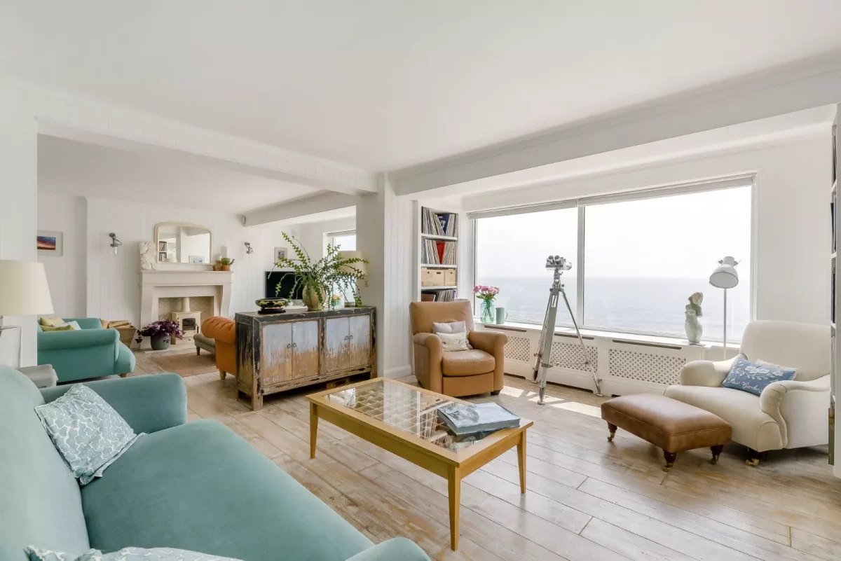 The open plan living room insie a property with a big window offering views over the beach