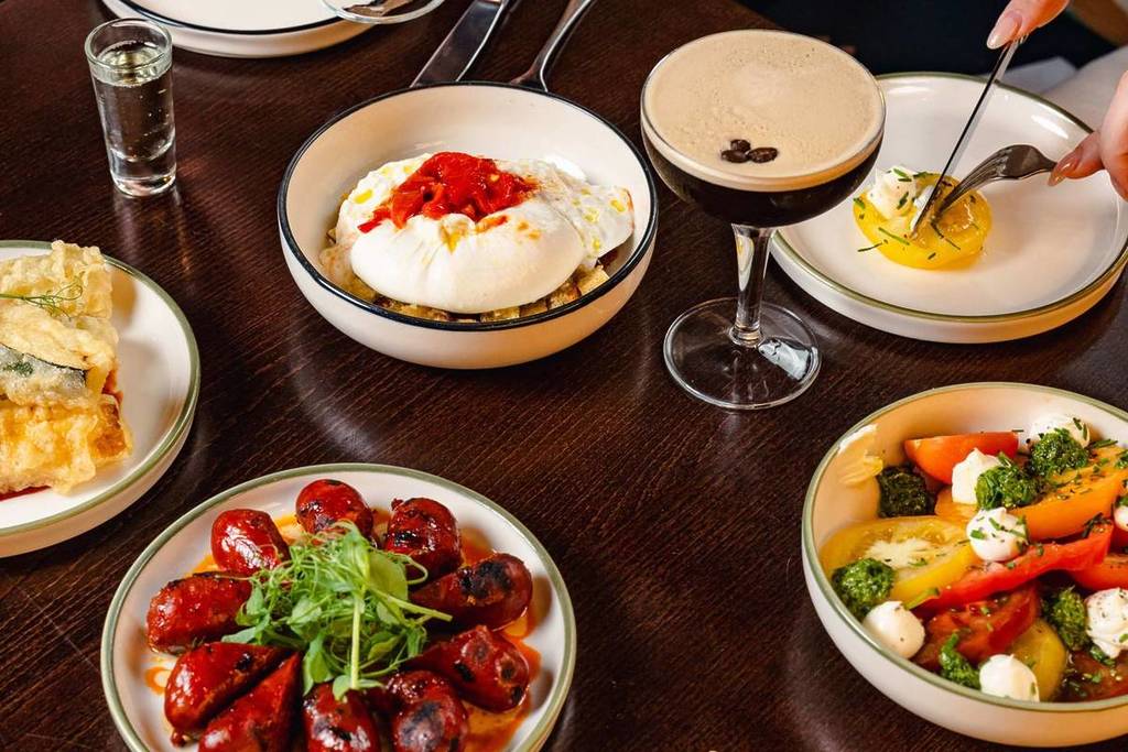 A vibrant spread of modern small plates and cocktails at Burdock, a stylish restaurant from the ETM Collection. Food is placed tidily in plates on a table, with a wave of colour and different culinary options arranged decadently.