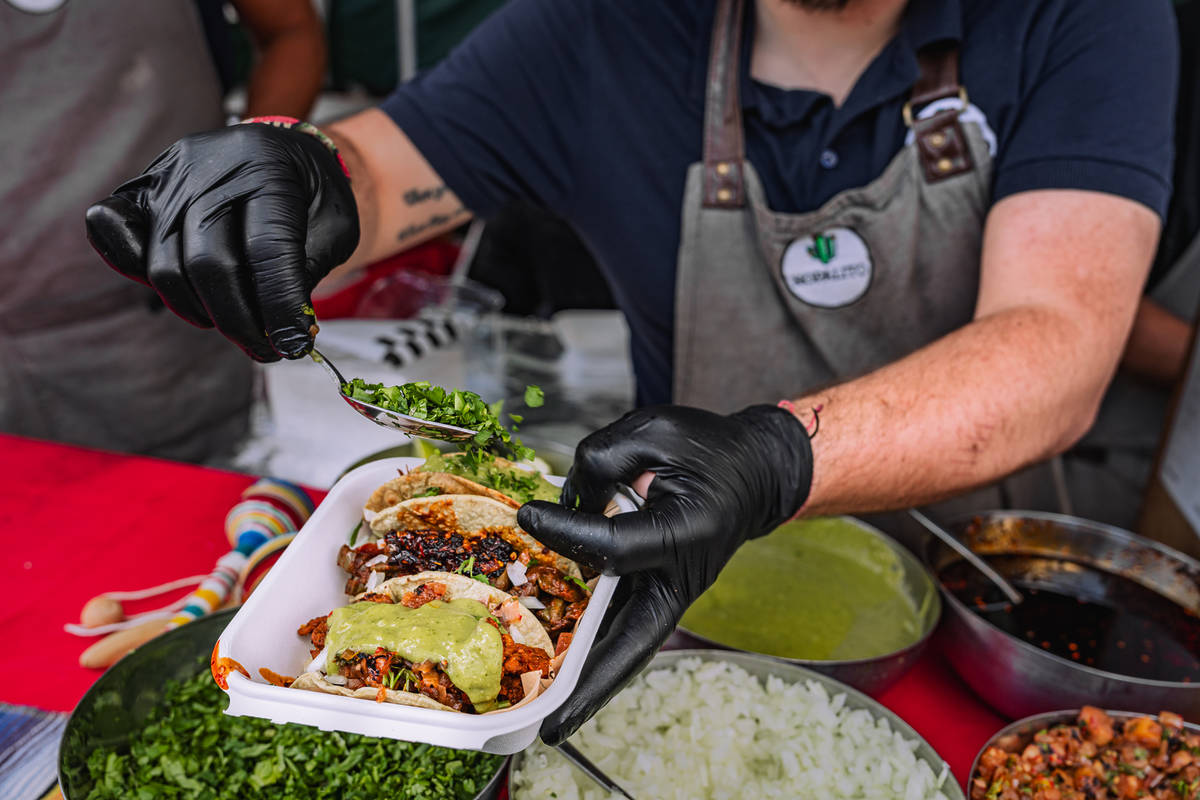 someone adding toppings to a tray of three tacos