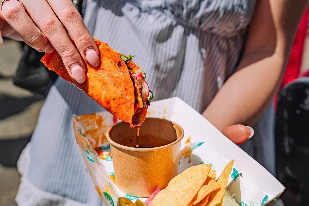 un taco de birria sumergido en una olla de consomé de ternera