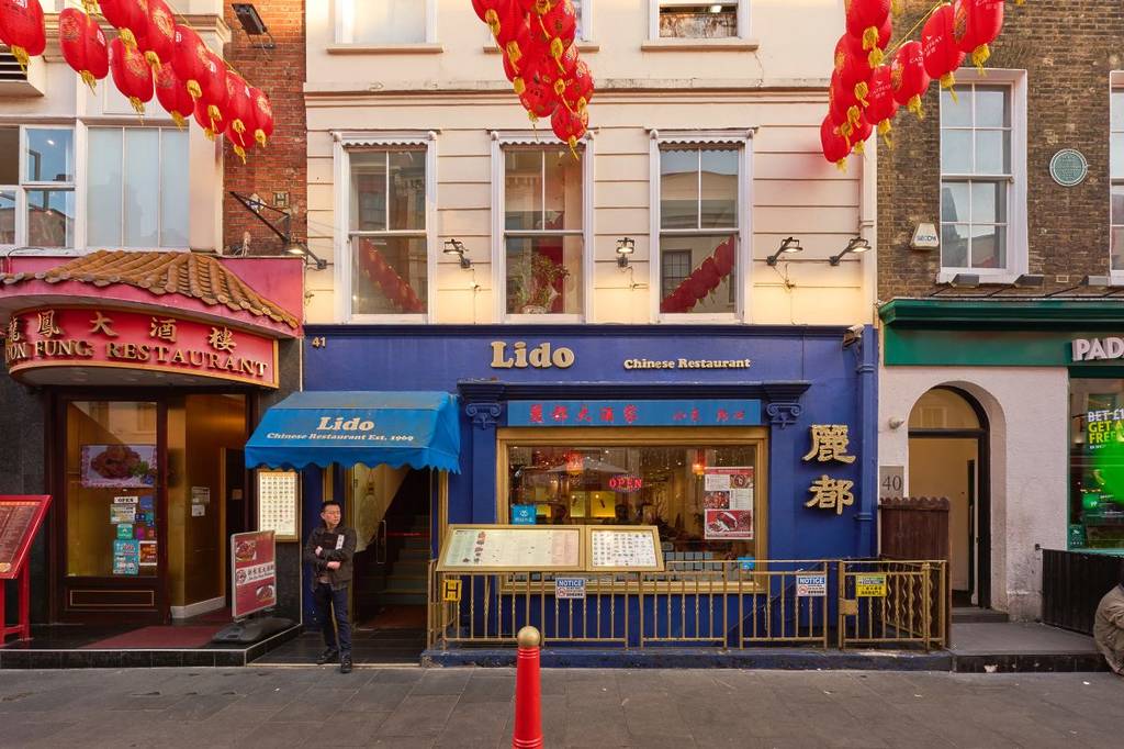 the blue exterior of Lido chinee restaurant, with someone stood waiting in the doorway