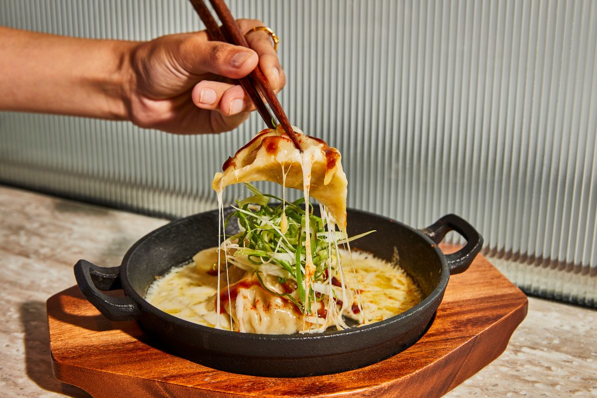 A plate of food with a gyoza being lifted out at Arcade Food Hall