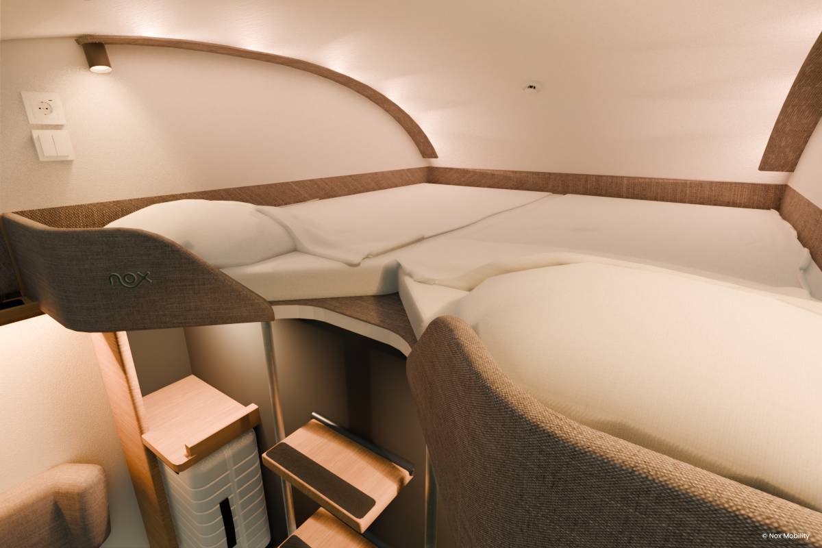A mock up of what a cabin inside the new nox sleeper trains with a bunk bed and a vew out onto some trees at nighttime