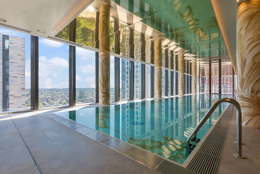 an indoor swimming pool with versace design and floor to ceiling windows with views of London
