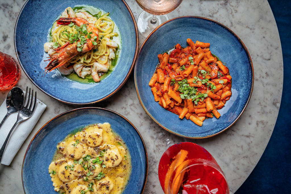 a flat lay of dishes laid out on a table, including a seafood spaghetti, a mushroom ravioli dish and a rigatoni in a red sauce