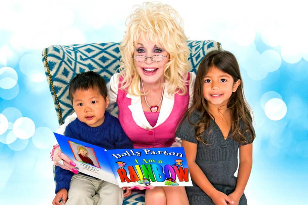 An image of Dolly Parton sat on an armchair reading a book wit h two children