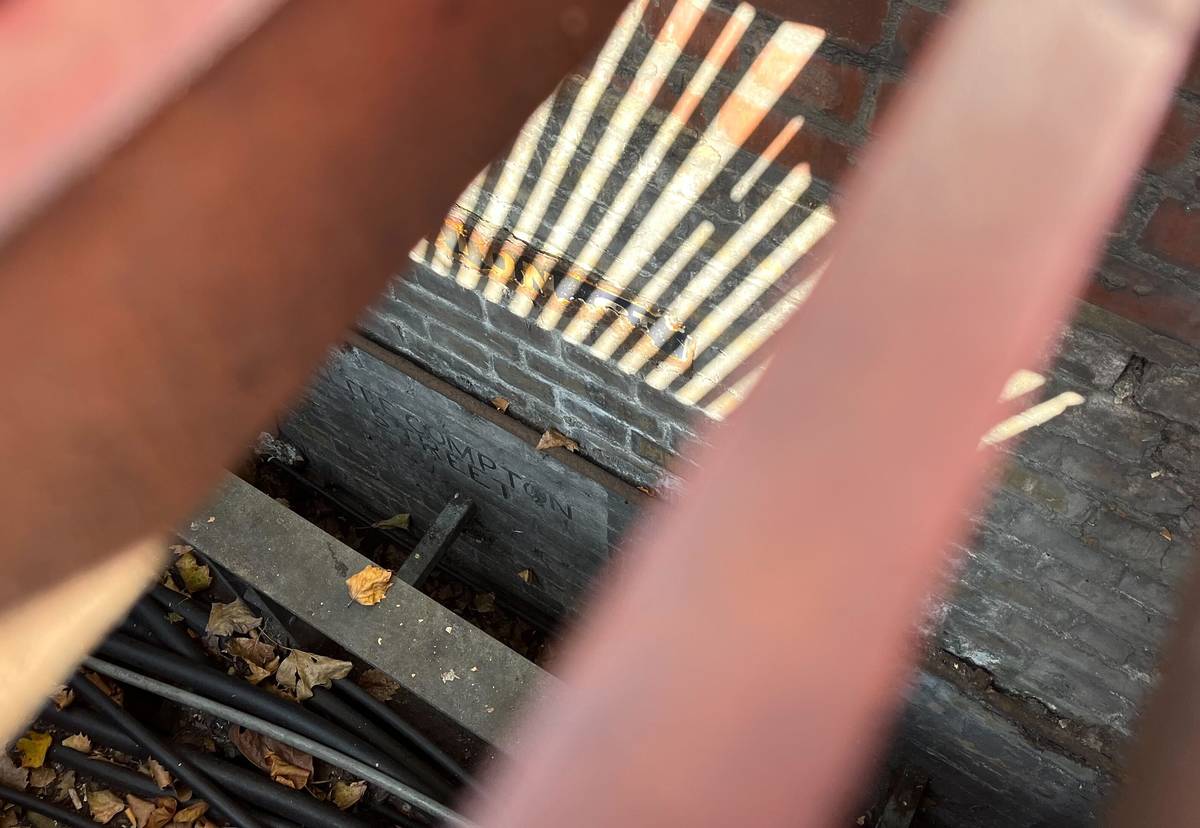 A Victorian street sigh through the bars of a metal grate