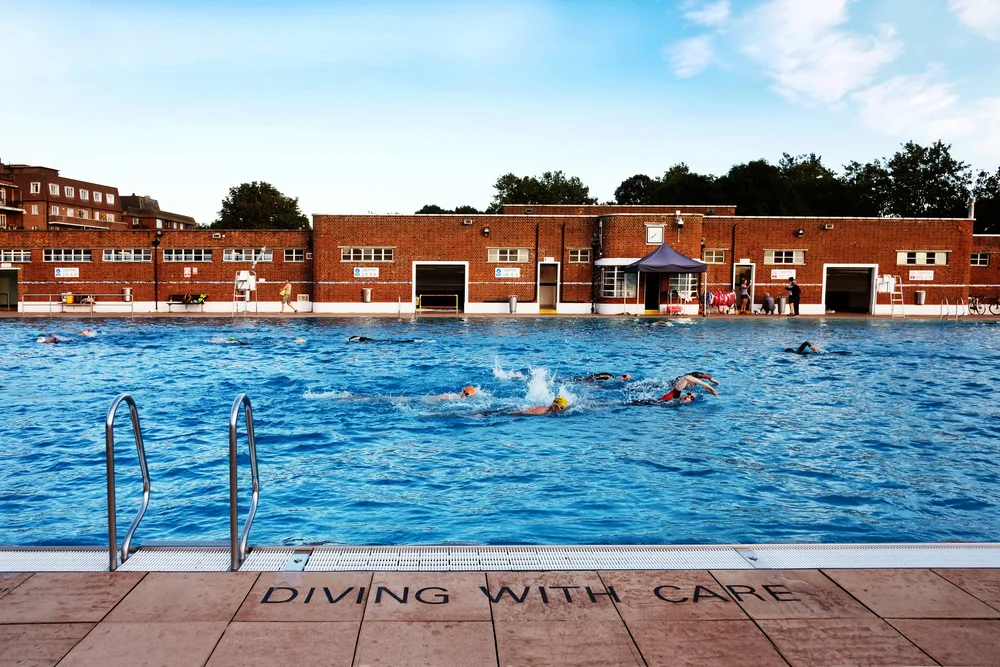 a photo of parliament hill lido with clear skies and an art deco building in the back